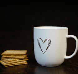 ceramic mug with a heart and crispbread on a wooden table