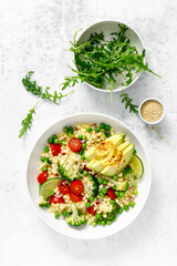 Couscous salad with broccoli, green peas, tomatoes, avocado and fresh arugula. Healthy natural plant based vegetarian food for lunch, israeli cuisine, top view