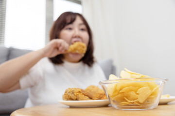 Obraz na płótnie Canvas Blurred Overweight Asian Woman Enjoy Eatting Fried Drumstick Chicken