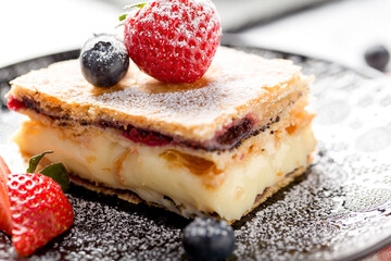 A piece of Napoleon cake with poppy seeds and cherries