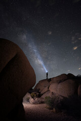 Man shining beam into Milky Way in Desert