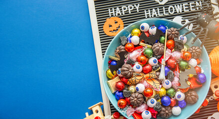 decorated holiday table Halloween Jack o Lantern candy bowl with sweets and halloween cookies Trick or Treat dark background