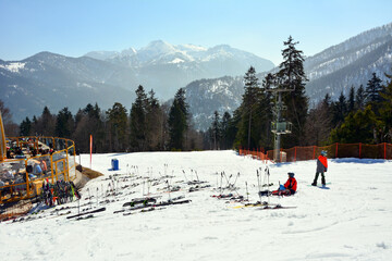 Several skiers of different ages and many ski poles with skis of vacationers on the ski slope