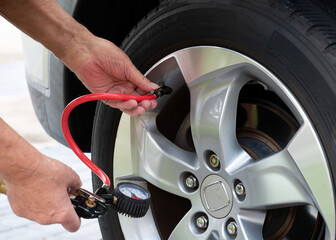 Car tire being inflated with hand held air compressor.