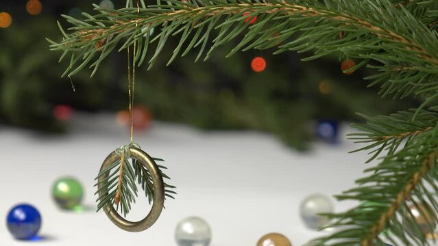 Handmade Christmas decoration from brass ring and spruce twig on the spruce branch against the background of spruce tree with Christmas lights, holiday concept