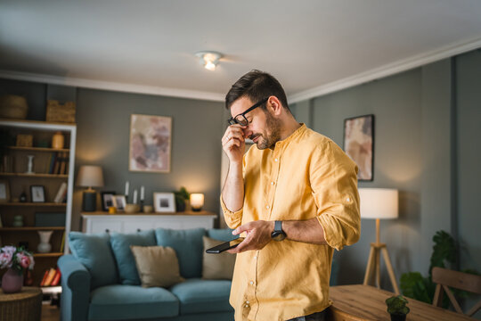 One adult man with eyeglasses at home use mobile phone have problem
