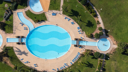The original round swimming pool with sun loungers in the garden, aerial view.