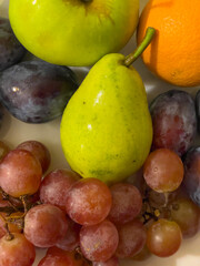 Fruit composition on a plate. Pear, grape, plum, orange