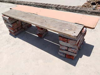 wooden plank on bricks for sitting people on this plank. bench used in rural area's shops schools and houses. Wooden bench made of two pieces of tree trunks and planks. resting place 