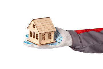 A man's hand in a construction suit and a white protective glove holds a toy wooden house.