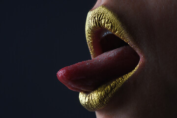 Sensual tongue licking lips. Golden glitter lipstick. Shine style for sexy lip. Sensual woman lips. Luxury golden mouth. Glamour gold lips. Golden lips with golden paint or metallic lipstick.