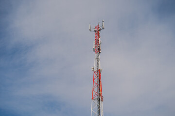 Radio and telecommunication tower with antennas and bright red and white colouring of metal