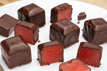 Chocolate candies cut with red berry filling on a white plate. 
