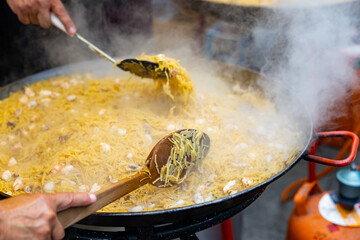 Appetizing racy seafood fideua, noodle paella with mussels, prawns and squid in large paellera....