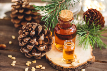 Organic essential oil, pine nuts, cedar cone on rustic wooden dark background. Concept of natural ingredients, naturopathy, herbal extracts and essence. Alternative medicine, aromatherapy