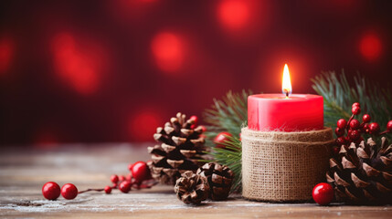 Burning red candle with christmas decorations against red background with copy space.