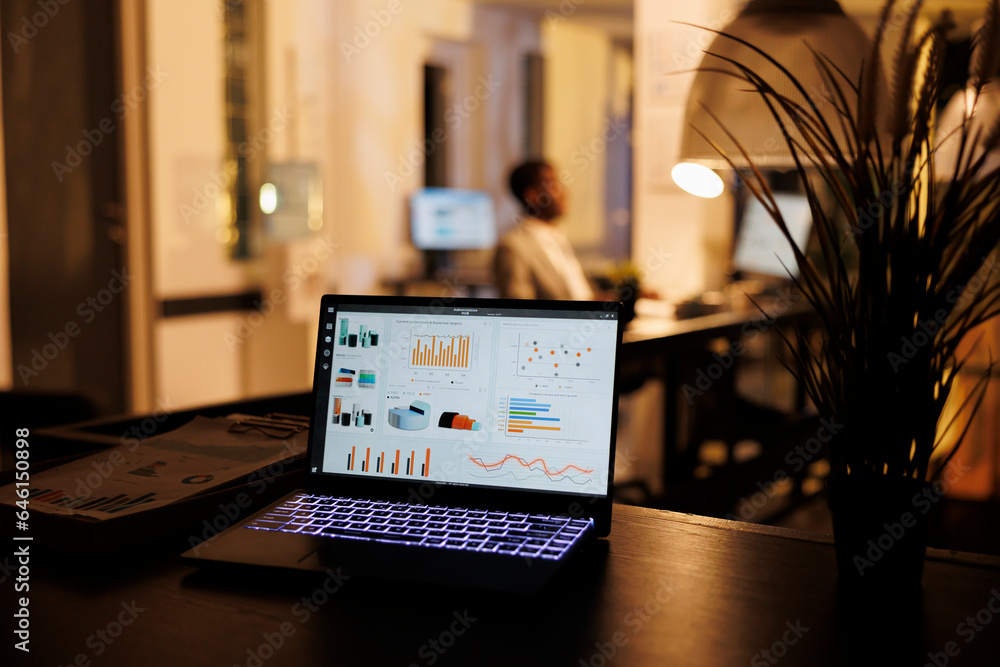 Aufkleber laptop computer with marketing data report standing on table in startup office, in background employ