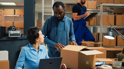 Small business owners doing quality control before shipping products order, packing merchandise in cardboard boxes. Workers preparing delivery and shipment in warehouse storage room.