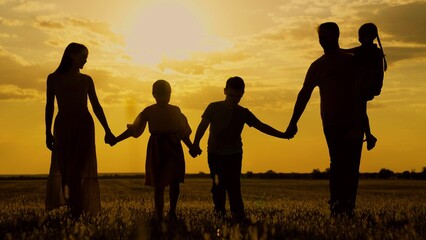 Active family with children walks in grass field in summer. Big family, group of people, nature. Silhouette family, Dad mom daughter son go hand in hand outdoors in autumn. Parental care for children