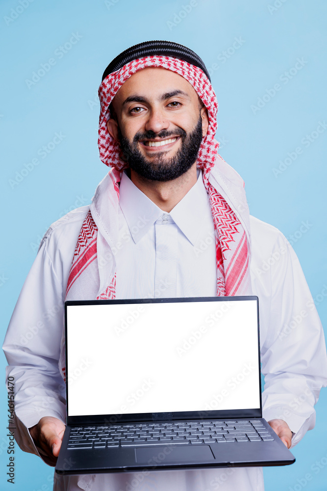 Aufkleber smiling muslim man showing laptop with blank screen mockup for software advertising portrait. arab p