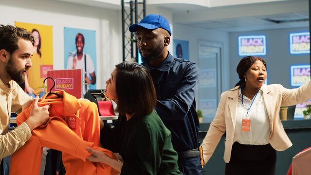 People into shopping madness during black friday sales, arguing over clothes with big discount. Angry customers pulling merchandise and being obsessed over promotional clearance items.