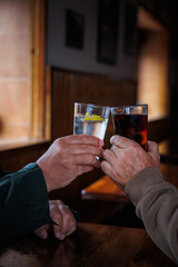 Two glasses of drink of two friends at the bar toasting on a wooden table