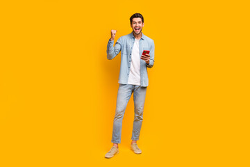 Photo of positive guy using device browsing web raise fist up winning isolated bright color background