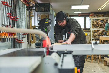 Man builder using a sliding saw table to cut wooden boards . High quality photo