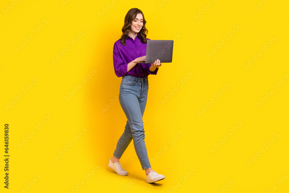 Poster full length profile portrait of positive lovely peron use netbook walking empty space isolated on ye