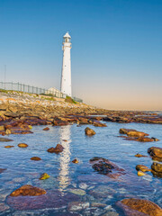 Obraz premium Slangkop Lighthouse and its reflection in the sea water during a clear afternoon, Kommetjie, Cape Town, South Africa