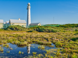 Fototapeta na wymiar Slangkop Lighthouse and its reflection in the water during a clear afternoon, Kommetjie, Cape Town, South Africa