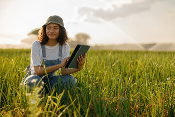 Naklejka na ściany i meble Professional woman farmer with digital tablet works in field. Agricultural business concept