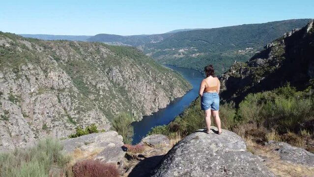 aerial shot of a woman standing on a viewpoint looking to the canyons of river Sil in Ribeira Sacara in Galicia, Spain