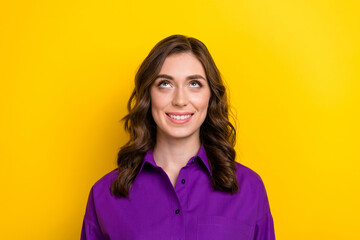 Portrait of toothy beaming lovely girl with curly hairdo wear violet blouse look up at sale empty space isolated on yellow background