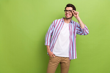 Photo of attractive young man wear striped shirt touching eyeglasses looking dreamy empty space advert isolated on green color background