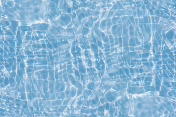 Blue water with ripples on the surface. Defocus blurred transparent blue colored clear calm water surface texture with splashes and bubbles. Water waves with shining pattern texture background.