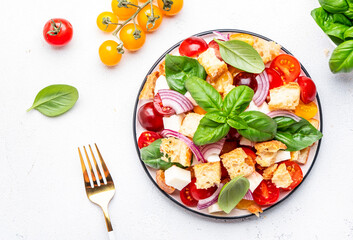 Panzanella vegetable salad with stale bread, colorful tomatoes, soft cheese, red onion, olive oil, salt and green basil, white background, top view