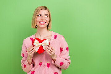 Photo of nice young woman blonde bob hair holding red cookies surprise heart look dream empty space isolated on green color background