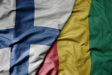 big waving national colorful flag of finland and national flag of guinea .