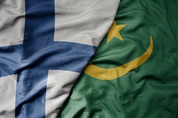 big waving national colorful flag of finland and national flag of mauritania .