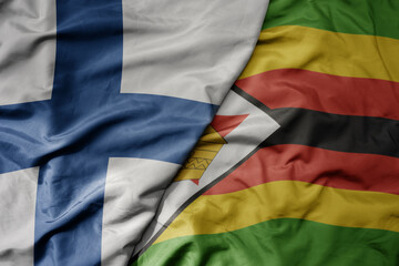 big waving national colorful flag of finland and national flag of zimbabwe .