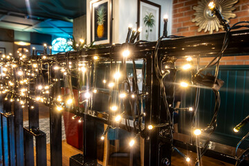 White fairy lights wrapped around a metal barrier in a bar to add mood and lighting