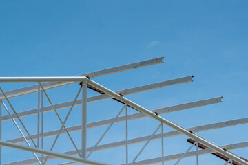 Structure of steel roof frame for building construction on blue sky background.