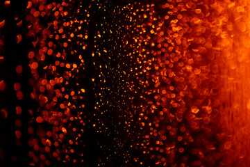 Background of blurred raindrops on glass at night in orange light. Abstract blurred background