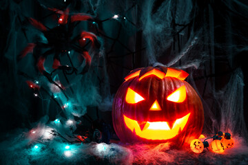 A glowing pumpkin for Halloween with a spider web and a spider.