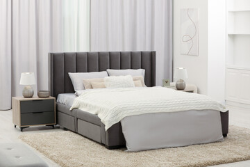 Stylish bedroom in soft light colors with comfortable bed and bedside tables. Interior design
