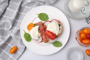 Delicious sandwich with burrata cheese, ham, radish and tomatoes served on light grey table, flat lay