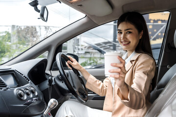 Asian woman holding coffee cup and sitting in a car