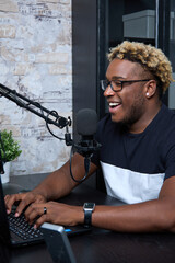 Radio DJ with glasses leads a popular program for listeners. Cheerful black podcaster at the...