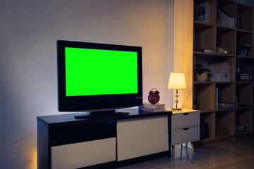 4K LCD TV with green chroma key on cabinet in the living room, white table and lamps indoors. Cozy living room, interior design